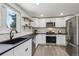 Well-lit kitchen featuring stainless steel appliances, black counter tops, and white cabinets at 1852 S Decatur St, Denver, CO 80219