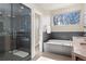 Bright bathroom featuring a glass shower, large tub with tile surround, and a window providing natural light at 2053 Meade St, Denver, CO 80211
