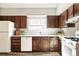 Bright kitchen featuring white countertops and dark wood cabinets and white appliances at 6156 W Jefferson Ave, Denver, CO 80235