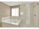 Bright bathroom featuring a shower, soaking tub, and large window for natural light at 10249 Trailriders Dr, Littleton, CO 80125