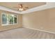 Large bedroom featuring a tray ceiling, neutral walls, and a large window for natural light at 10249 Trailriders Dr, Littleton, CO 80125
