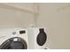 Bright laundry room with white front-loading washer and dryer set and shelf at 10249 Trailriders Dr, Littleton, CO 80125