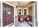 Charming front porch, adorned with welcome sign, red chairs, decorative pillows, and brick accents at 15886 E Stargazer Ln, Parker, CO 80134