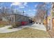 A detached garage and a small yard area and a red outdoor chair are featured in the home's backyard at 1355 Hudson St, Denver, CO 80220
