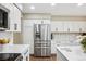 Modern kitchen features stainless steel refrigerator, white cabinets, and hardwood floors at 775 Poppywood Dr, Highlands Ranch, CO 80126