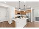 Modern kitchen features stainless steel appliances, an island with sink, and wood cabinets, perfect for cooking and entertaining at 8777 Whiteclover St, Littleton, CO 80125