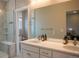 Bathroom with double vanity, large mirrors, and walk-in shower with built-in bench at 10018 E 62Nd Ave, Denver, CO 80238
