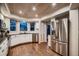 Well-lit kitchen with stainless steel appliances, white cabinets, and gorgeous wood flooring at 13076 Marion Dr, Thornton, CO 80241