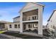 Back exterior view with a covered patio and balcony with wrought iron railing on a sunny day at 6400 Barnstead Dr, Castle Pines, CO 80108
