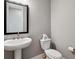Powder room featuring a pedestal sink, framed mirror, and modern fixtures, exuding simple elegance at 6400 Barnstead Dr, Castle Pines, CO 80108