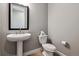 Powder room featuring a pedestal sink, framed mirror, and modern fixtures, exuding simple elegance at 6400 Barnstead Dr, Castle Pines, CO 80108