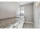 Laundry room with granite countertop, white cabinets, and patterned tile flooring at 6400 Barnstead Dr, Castle Pines, CO 80108