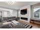 Open living room with a fireplace feature wall, modern lighting, and a large sectional at 6400 Barnstead Dr, Castle Pines, CO 80108