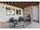 Covered patio with stone fireplace, four chairs, a table and a black and white striped rug at 6400 Barnstead Dr, Castle Pines, CO 80108