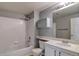 Bright bathroom featuring a shower over tub with white tile surround and vanity with light countertop at 7440 S Blackhawk St # 12-204, Englewood, CO 80112