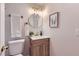 Well-lit bathroom with a wood vanity, modern fixtures, and a decorative mirror at 12932 E Elgin Pl, Denver, CO 80239