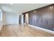 Open-concept living room boasting stylish wood-look floors, a unique accent wall, and a view of the staircase at 12932 E Elgin Pl, Denver, CO 80239