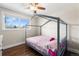 Cozy bedroom featuring hardwood floors, a bright window, and a unique canopy bed frame at 3395 W Union Ave, Englewood, CO 80110