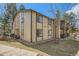 Exterior side view of the condo building with a stone chimney and grassy area at 1864 S Pitkin Cir # B, Aurora, CO 80017