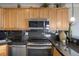 Kitchen with maple wood cabinets, black counters and backsplash and stainless steel appliances at 909 N Logan St # 11A, Denver, CO 80203