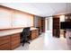 Finished basement featuring white tile flooring, built-in desk, shelving, and natural light from window at 17530 E Caspian Pl, Aurora, CO 80013