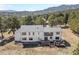 Aerial view of a two-story home with large windows and backyard deck featuring a mountain backdrop at 2999 Olympia Cir, Evergreen, CO 80439
