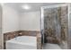 Bright bathroom featuring a soaking tub with decorative tile surround and a glass-enclosed shower with mosaic tile at 8100 E Union Ave # 712, Denver, CO 80237