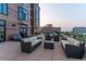 Outdoor patio with comfortable seating, lounge chairs, and views of city buildings at dusk at 8100 E Union Ave # 712, Denver, CO 80237