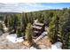 Aerial view of a wood home nestled among dense evergreens, fenced yard, and snow-dusted ground at 10858 Norton Ave, Conifer, CO 80433