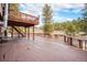 Large wooden deck with railing offers ample space for outdoor furniture, overlooking a treed landscape at 10858 Norton Ave, Conifer, CO 80433