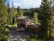 Exterior view of a charming two-story home with a deck and a detached garage nestled among trees at 10858 Norton Ave, Conifer, CO 80433