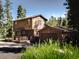 Charming two-story home with a deck and detached garage, surrounded by lush greenery and flowers at 10858 Norton Ave, Conifer, CO 80433