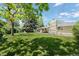 Spacious backyard with lush lawn, mature trees, and a covered patio, perfect for outdoor activities at 11328 W 27Th Ave, Lakewood, CO 80215