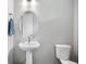 Powder room featuring a pedestal sink, oval mirror, and toilet against a neutral wall at 7040 Homeplace St, Castle Rock, CO 80108