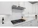 Stylish kitchen with white cabinets, stainless steel range hood, and a sleek cooktop on quartz countertops at 7040 Homeplace St, Castle Rock, CO 80108
