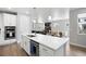 Open kitchen with white cabinets, quartz countertops, stainless appliances, and an island with seating at 7040 Homeplace St, Castle Rock, CO 80108