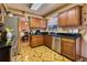 Functional kitchen featuring wood cabinetry, black countertops, and stainless steel appliances, adjoining the dining room at 3035 S Biscay St, Aurora, CO 80013