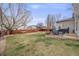 Backyard with a firepit, seating area, lush green grass, and trees at 1495 Hummingbird Cir, Brighton, CO 80601