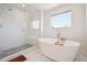 Elegant bathroom featuring a freestanding tub, glass-enclosed shower, and bright natural light from a window at 2480 Quitman St, Denver, CO 80212