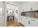 Bright kitchenette area with white cabinets, granite counters, and an open view to the dining room at 2480 Quitman St, Denver, CO 80212