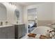 Bathroom with double vanities, soaking tub with wooden tray, and view into the bedroom at 6581 E Heritage Pl, Englewood, CO 80111