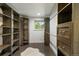Walk-in closet with custom built-in shelves, drawers, and wood floors with a white rug at 6581 E Heritage Pl, Englewood, CO 80111
