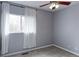 Neutral bedroom with ceiling fan, window with white curtains, and gray walls at 11149 Gaylord St, Northglenn, CO 80233