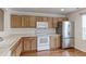 Kitchen with stainless steel refrigerator, white appliances, and wood cabinets at 11149 Gaylord St, Northglenn, CO 80233