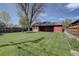 Large grassy backyard with a red brick house and mature trees at 782 Holly St, Denver, CO 80220