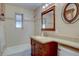 Bathroom features a tiled shower and bath with a wood vanity and framed mirror at 782 Holly St, Denver, CO 80220