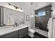 Modern bathroom featuring a sleek vanity, large mirror, and a glass-enclosed shower with gray tile and black fixtures at 15191 Dinosaur Ridge Rd, Morrison, CO 80465