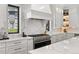Sleek, modern kitchen featuring a professional grade stove, marble backsplash and custom cabinetry at 15191 Dinosaur Ridge Rd, Morrison, CO 80465