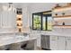Bright kitchen featuring open shelving, stainless appliances, and a large farmhouse style sink at 15191 Dinosaur Ridge Rd, Morrison, CO 80465