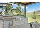 Outdoor grilling area featuring a stone backsplash and counter, stainless steel grill, and a view at 15191 Dinosaur Ridge Rd, Morrison, CO 80465